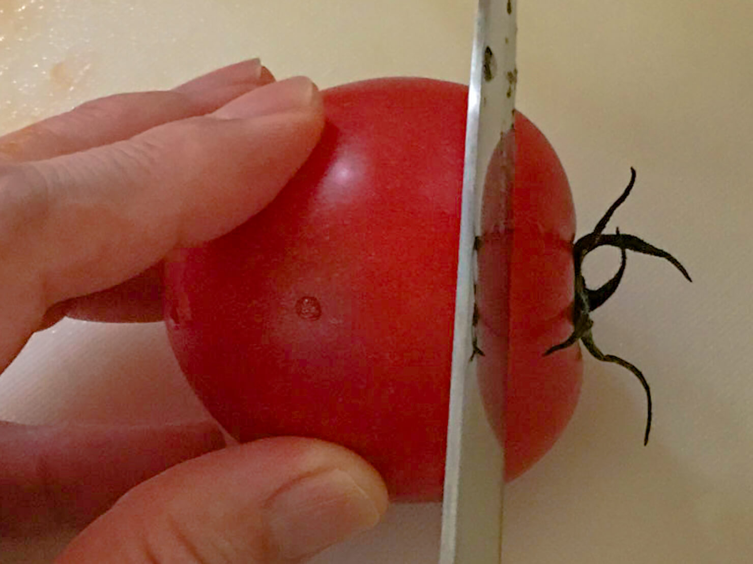 トマトの上の部分を切っている写真