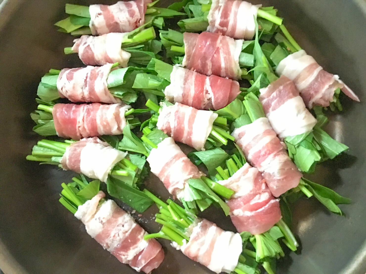 空芯菜の豚バラ肉巻きをフライパンに置いた写真